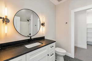 Bathroom featuring vanity, dark tile patterned flooring, and a shower