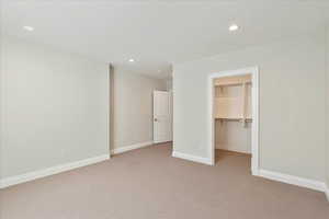 Unfurnished bedroom featuring recessed lighting, a spacious closet, and light carpet