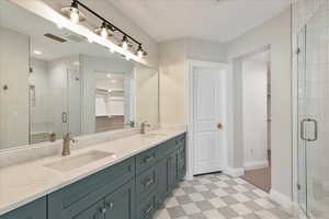 Full bathroom with a spacious closet, double vanity, a shower stall, and light flooring