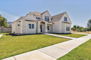 Modern farmhouse with board and batten siding, a standing seam roof, a front yard, a shingled roof, and a metal roof