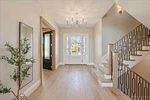 Entryway with light wood-type flooring and a chandelier