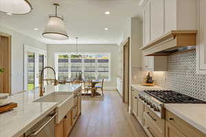 Kitchen featuring light stone countertops, recessed lighting, light wood-type flooring, appliances with stainless steel finishes, and pendant lighting