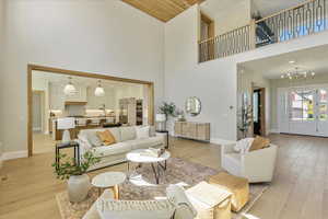 Living room with a high ceiling, light wood-style floors, and a chandelier