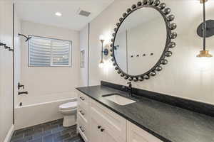 Full bathroom featuring shower / washtub combination, vanity, dark tile patterned floors, and recessed lighting