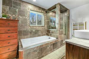 Full bath with vanity, a shower stall, radiator, light tile patterned floors, and a bath