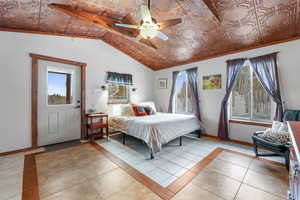 Bedroom with light tile patterned floors, an ornate ceiling, lofted ceiling, and ceiling fan