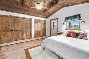 Bedroom featuring light tile patterned floors, multiple closets, ceiling fan, vaulted ceiling, and an ornate ceiling