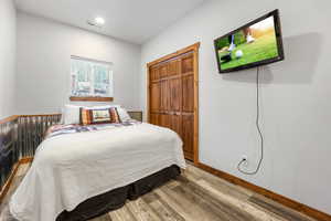 Bedroom with wood finished floors and a closet