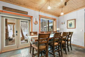 Dining space featuring french doors, wood ceiling, and concrete flooring