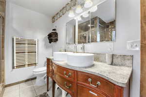 Full bath featuring radiator heating unit, a shower stall, vanity, and light tile patterned floors