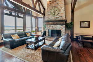 Living area with high vaulted ceiling, hardwood / wood-style floors, a fireplace, and a water view
