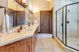 Full bath featuring double vanity, a stall shower, and lofted ceiling