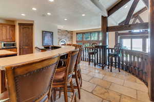 Kitchen featuring stone tile floors, light countertops, recessed lighting, a textured ceiling, and a kitchen bar