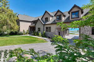 View of front of property featuring stucco siding, stone siding, and a front lawn