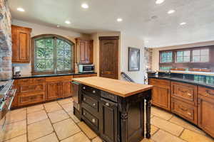 Kitchen featuring dark cabinetry, wooden counters, brown cabinets, recessed lighting, and a textured ceiling