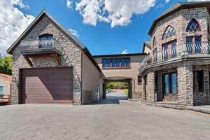 View of front of home with a balcony, driveway, french doors, and stucco siding