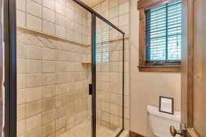 Full bathroom featuring a shower stall and toilet