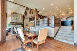 Dining space featuring stairway, wood-type flooring, recessed lighting, a brick fireplace, and high vaulted ceiling