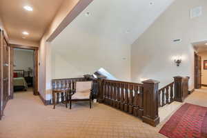 Hallway featuring an upstairs landing, high vaulted ceiling, light carpet, and recessed lighting