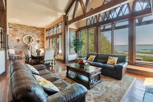 Living room with hardwood / wood-style flooring, a water view, a high ceiling, beamed ceiling, and recessed lighting