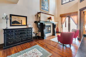Primary bedroom featuring a towering ceiling, hardwood / wood-style floors, and a tile fireplace with imported mantle, sitting area.