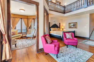 Primary Bedroom with hardwood / wood-style floors sitting room and a high ceiling