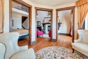 Primary bedroom sitting area with light wood-style floors, a fireplace, and stairs