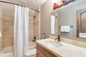 Full bath with shower / bath combination with curtain, vanity, and a textured ceiling