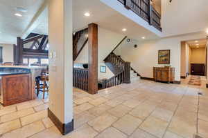 Living area with recessed lighting, stone tile flooring, stairway, and beam ceiling