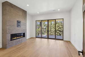 Unfurnished living room featuring a fireplace, light wood finished floors, and recessed lighting
