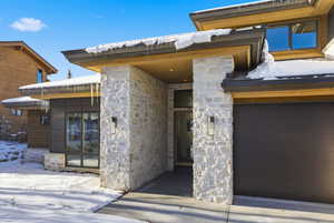 Snow covered property entrance featuring stone siding