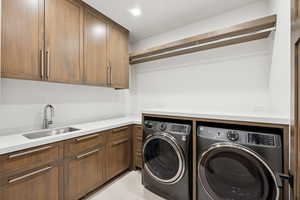 Washroom featuring washing machine and dryer, cabinet space, light tile patterned floors, and recessed lighting