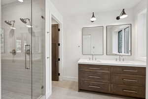Full bath with a stall shower, double vanity, and light tile patterned floors