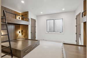 Unfurnished bedroom with light carpet, recessed lighting, and wood walls