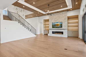 Unfurnished living room with wood ceiling, light wood finished floors, stairway, a fireplace, and built in shelves