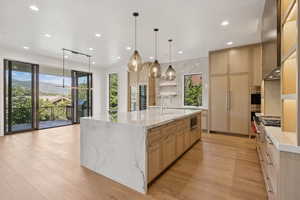 Kitchen featuring light brown cabinetry, open shelves, light stone countertops, light wood-style flooring, and recessed lighting