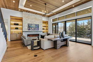 Living room with wood ceiling, a tray ceiling, light wood-style floors, a large fireplace, and stairway