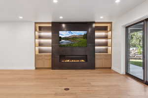 Detailed view of built in shelves, wood finished floors, recessed lighting, and a large fireplace
