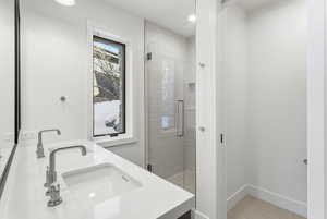 Bathroom featuring double vanity, a stall shower, and light tile patterned flooring