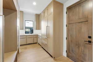 Kitchen featuring light brown cabinetry, light countertops, light wood-style flooring, paneled built in fridge, and recessed lighting