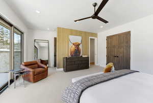 Carpeted bedroom featuring ceiling fan, wood walls, recessed lighting, and an accent wall