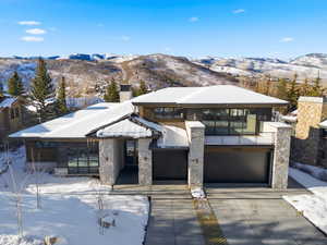 View of front of house with a chimney, a mountain view, driveway, a balcony, and an attached garage