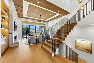 Stairs with a fireplace, a ceiling fan, a tray ceiling, wood ceiling, and a towering ceiling