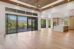 Unfurnished living room featuring a mountain view, recessed lighting, wood ceiling, light wood-type flooring, and a chandelier