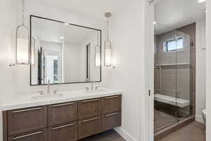 Bathroom with a stall shower, double vanity, dark tile patterned flooring, and recessed lighting