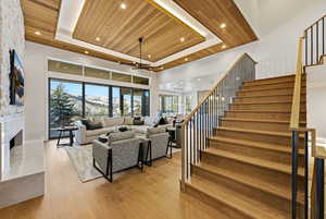 Living room with wooden ceiling, a raised ceiling, a mountain view, light wood-style floors, and stairs