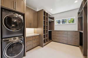 Laundry area featuring stacked washing machine and dryer, recessed lighting, and cabinet space