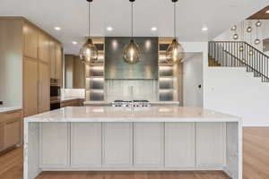 Kitchen featuring light stone countertops, pendant lighting, light wood-style floors, and recessed lighting
