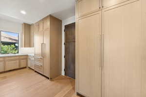 Kitchen with light brown cabinetry, light wood-type flooring, light countertops, recessed lighting, and paneled fridge