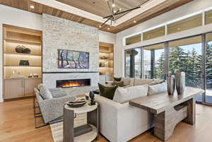Living room with built in shelves, wood ceiling, light wood-type flooring, a large fireplace, and recessed lighting